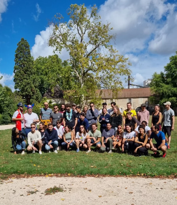 Ensemble des 34 participants à la première course organisé par Mauvais joueur en 2022. Les 34 personnes posent ensemble avant le départ de la course à Dijon, dans un parc avec des arbres, il fait beau, le ciel est bleu.