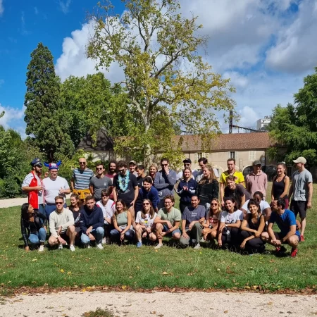 Ensemble des 34 participants à la première course organisé par Mauvais joueur en 2022. Les 34 personnes posent ensemble avant le départ de la course à Dijon, dans un parc avec des arbres, il fait beau, le ciel est bleu.